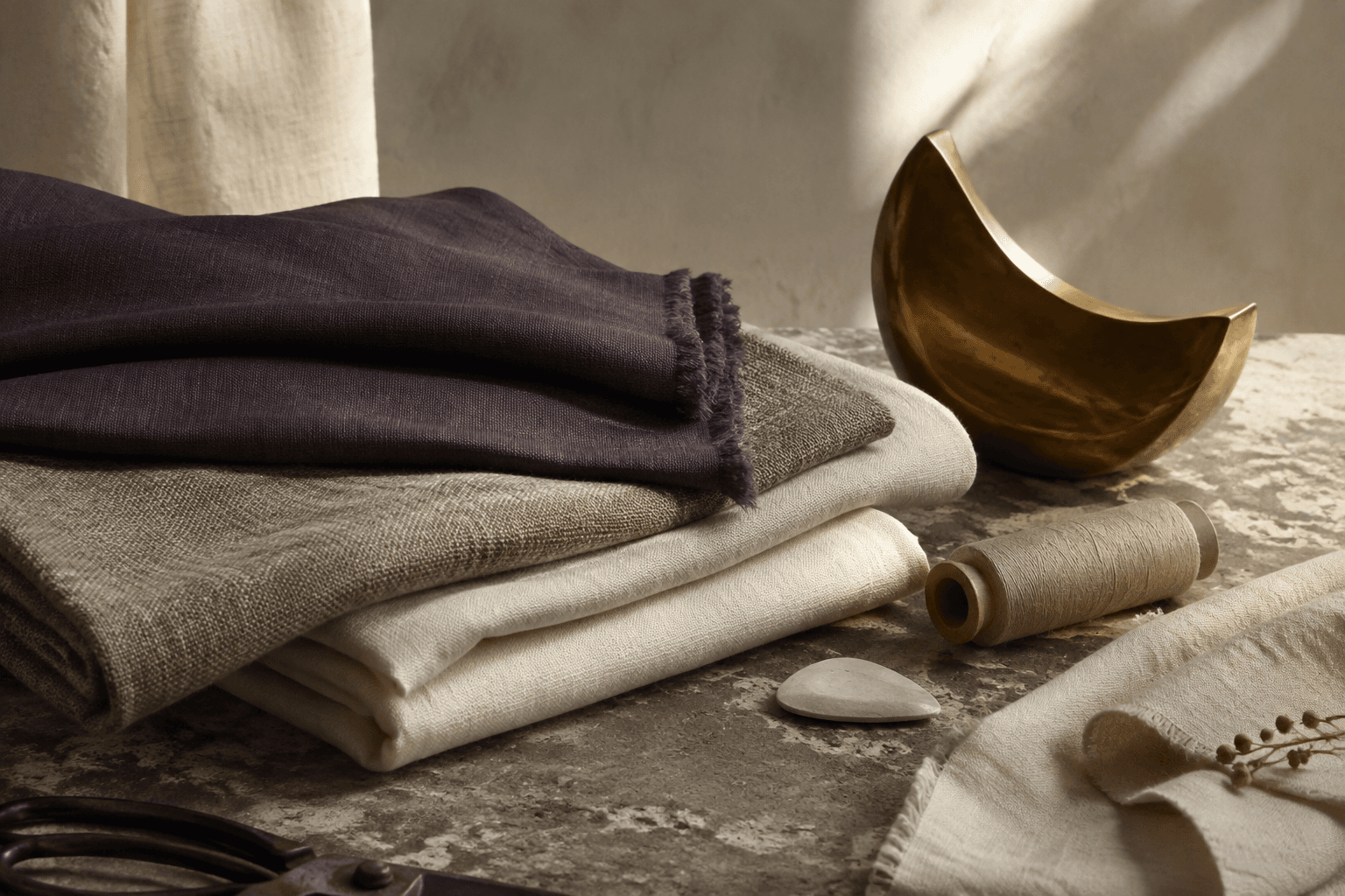 Natural textiles, thread and a brass object on stone